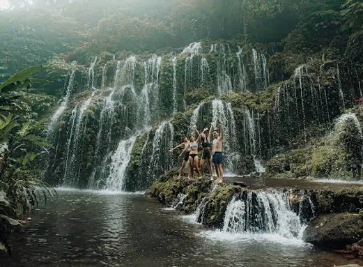 Group standing near a waterfall in Munduk surrounded by lush tropical forest