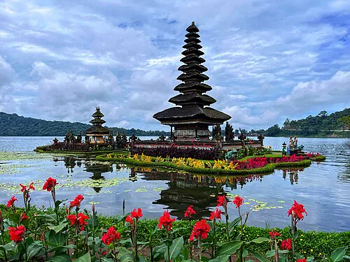 Ulun Danu Beratan temple on the lake with mountains and flowers in the foreground