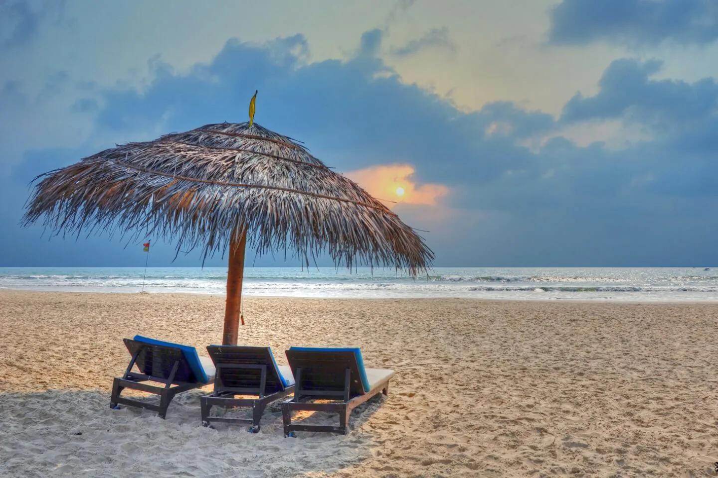 Benaulim Beach in South Goa with a thatched umbrella, loungers and a calm shoreline at sunset