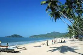 Palolem Beach in South Goa with a crescent bay, clear water, people on the sand and palm shade