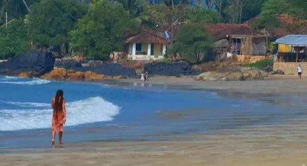 Patnem Beach in South Goa with a quiet shoreline, waves and beach cottages among palms