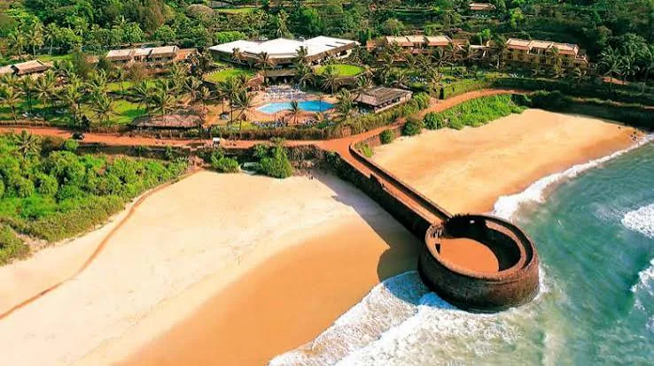 Sinquerim Beach in North Goa with Fort Aguada, a curved shoreline and resort greenery