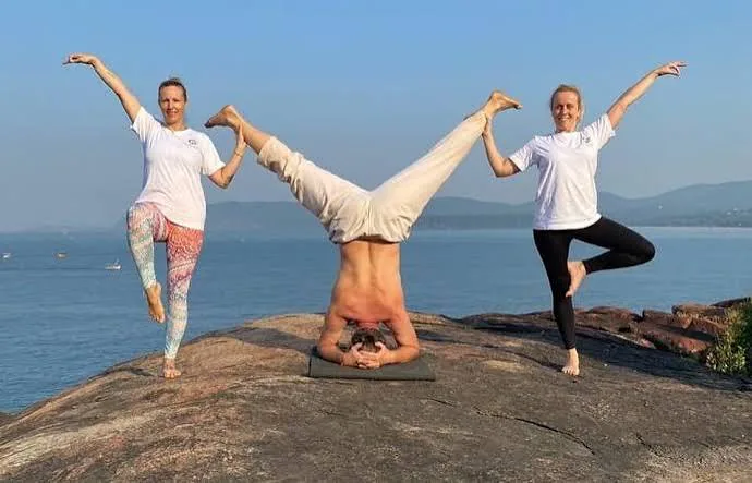 Wellness morning in Goa with people practicing yoga on a rocky coastline by the sea