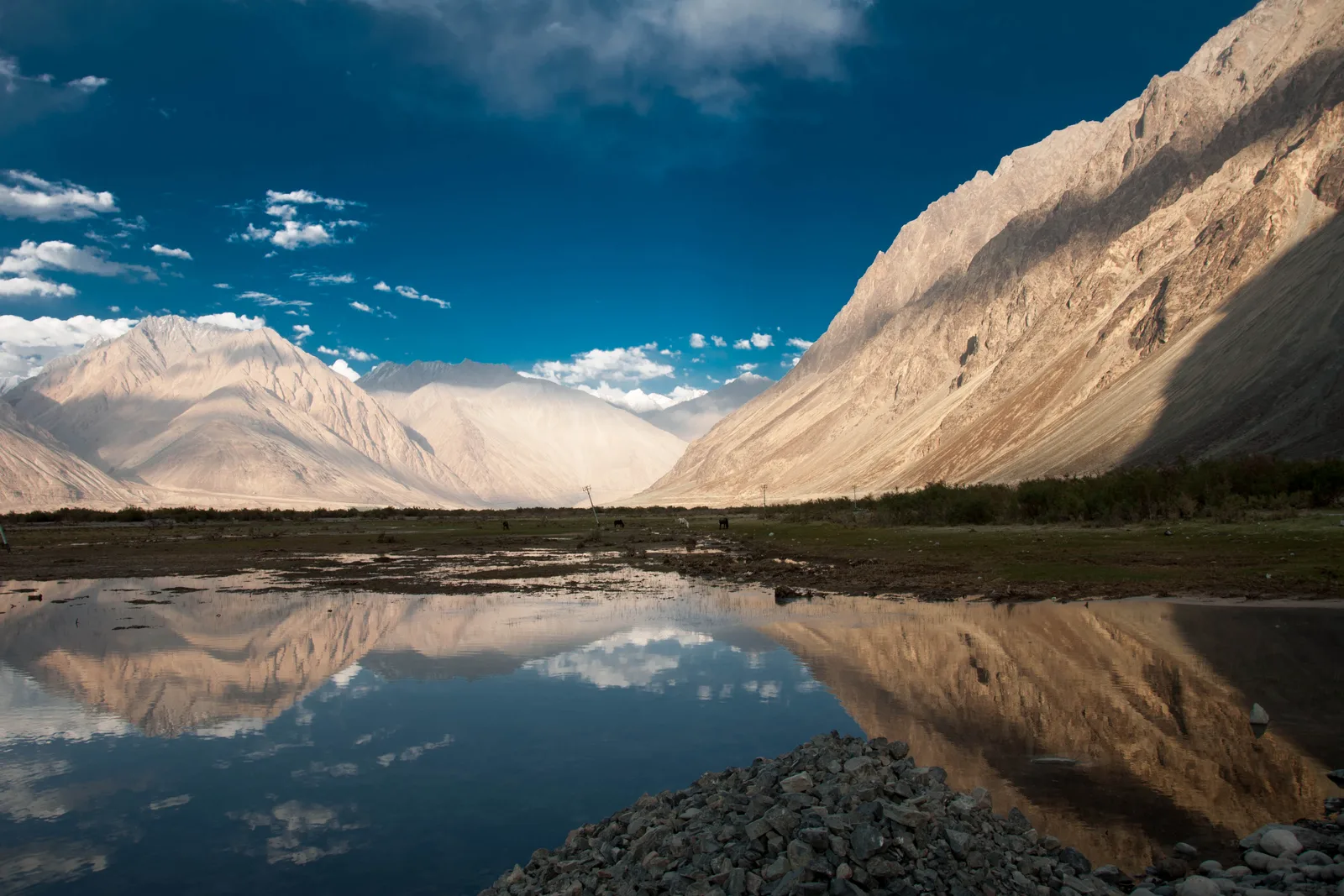 A reflective river beneath the high mountains of Hunder in Nubra Valley