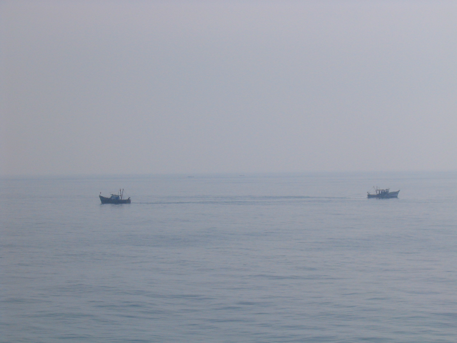 Small boats crossing the pale blue waters around a Lakshadweep lagoon